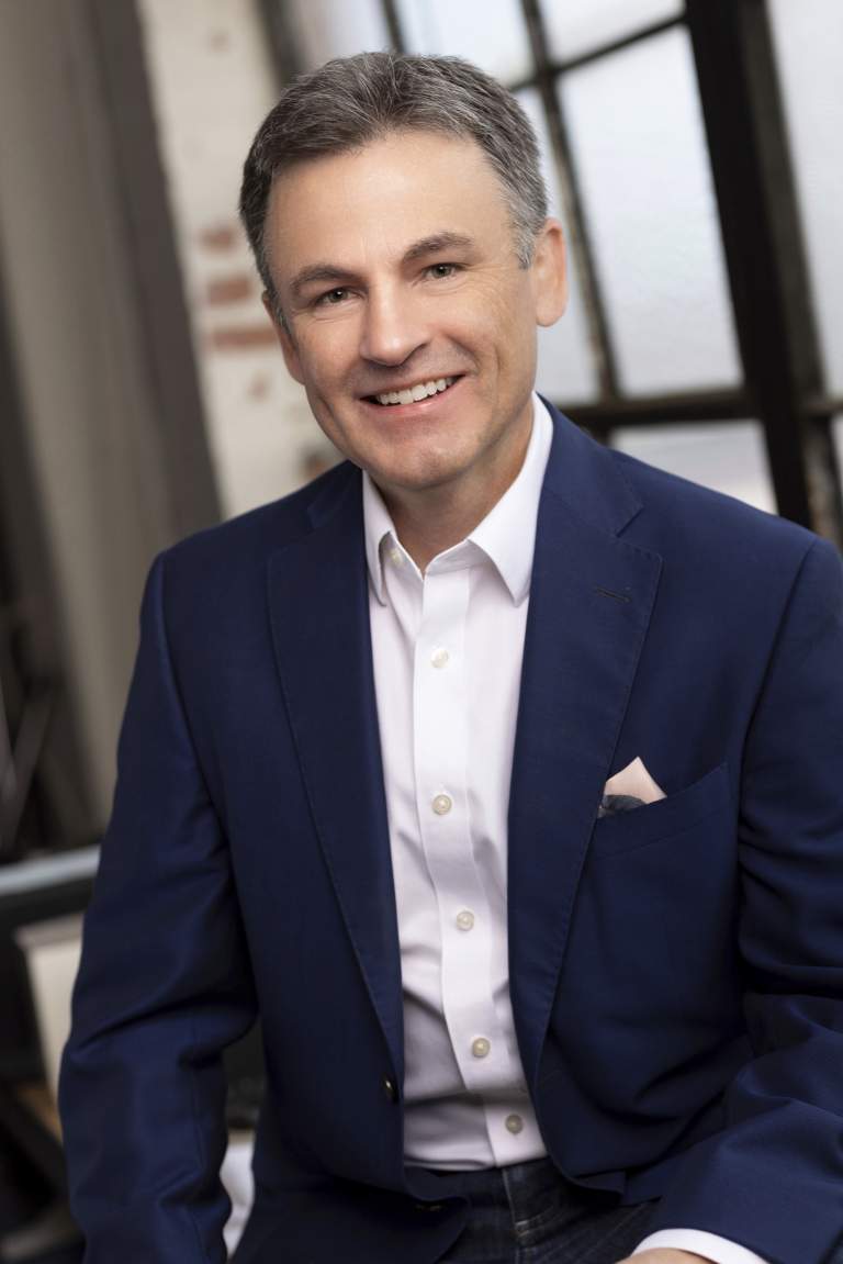 author Tin Bohen in blue suit with pocket scarf